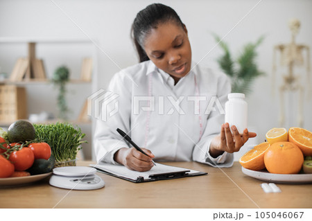 Female with medicine bottle writing on paper in office 105046067