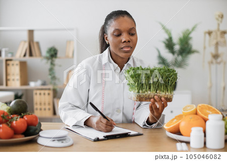 Nutritionist writing meal diet with sprouts in hand at work 105046082