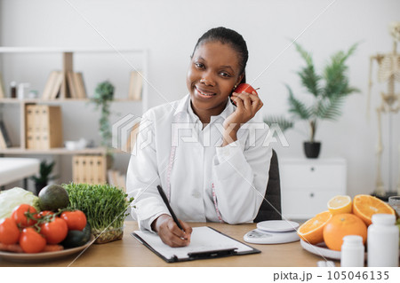 Nutritionist posing with apple close to cheek at doctor's Nutritionist posing with apple close to cheek at doctor's 105046135