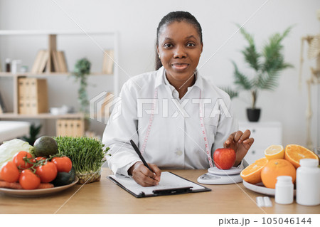 Professional assessing apple on scales in consulting room 105046144