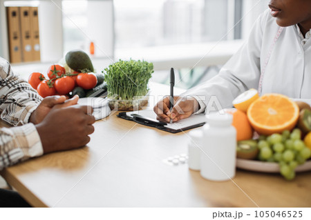 Nutritionist making notes at desk with medicine and products Nutritionist making notes at desk with medicine and products 105046525
