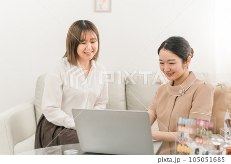 ネイルサロンでパソコンを使ってネイリストにカウンセリングを受けるアジア人女性 105051685