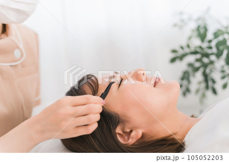 まつげエクステを施術するアイリスト 105052203