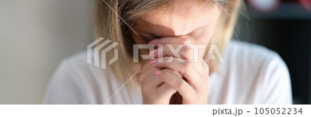 Stressed sad woman with closed eyes keeps her hands connected near her face close-up. 105052234