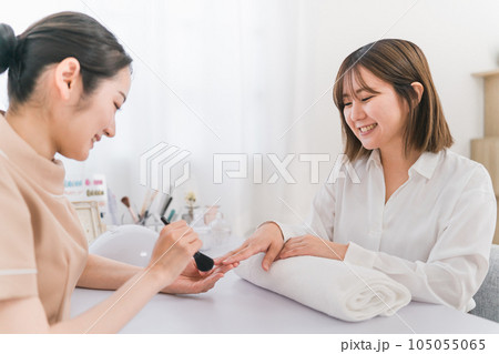 ネイルサロンでダストブラシを使って爪の粉を払うネイリスト 105055065