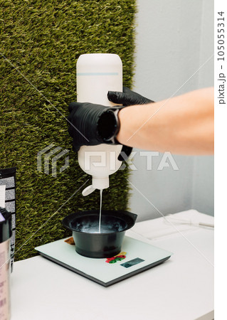 A hairdresser pours an oxidizer. The process of preparation before coloring hair 105055314