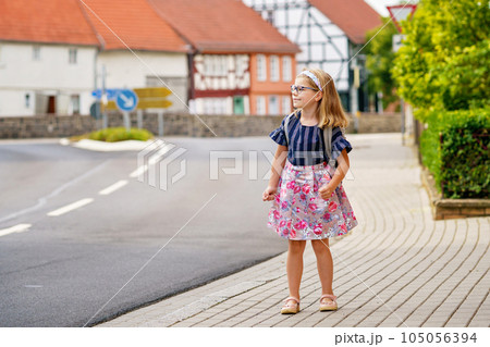 Little Preschool Girl on the Way to School. Healthy Happy Child Walking to Nursery School and Kindergarten. Smiling Child with Eyeglasses and Backpack on the City Street, Outdoors. Back to School. 105056394
