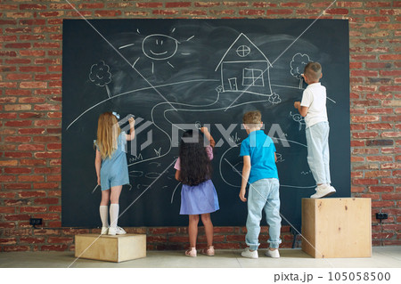 Little boys and girls, children drawing on blackboard, spending time together, studying, learning, playing Little boys and girls, children drawing on blackboard, spending time together, studying, learning, playing 105058500