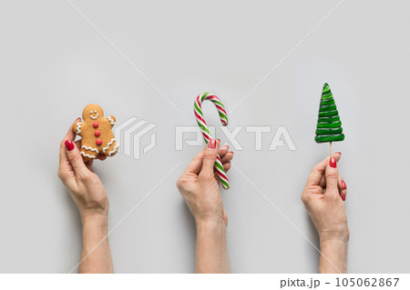 Christmas traditional food in hand holding gingerbread, lollipop, candy cane. Christmas traditional food in hand holding gingerbread, lollipop, candy cane. 105062867