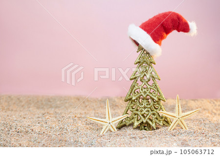 Golden Christmas tree with Santa's hat and starfish on sand. Christmas, New Year. Copy space 105063712