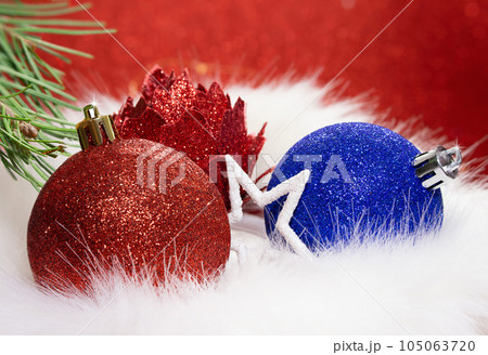 Red, blue shiny ball and flower with star with fir branch on fur from behind blurred background. Christmas, New Year. Copy space Red, blue shiny ball and flower with star with fir branch on fur from behind blurred background. Christmas, New Year. Copy space 105063720