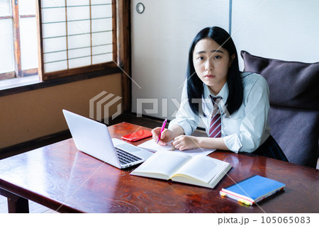 勉強に飽きてノートに落書きをする女子高生 105065083