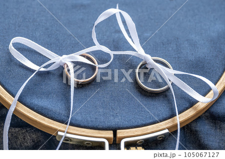 Close-up view of golden wedding rings on blank decorative stiching ring pillow 105067127