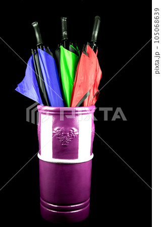 Assorted Umbrellas in a Painted Chimney Pot Umbrella Stand on a Black Background 105068639