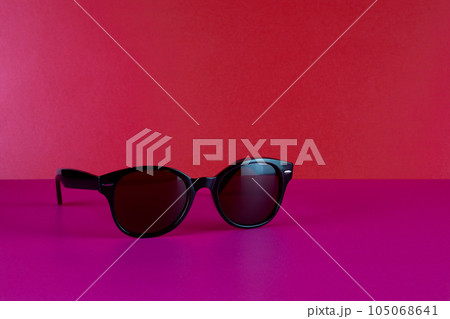 Designer Sunglasses on a Pink Surface with Red Background Designer Sunglasses on a Pink Surface with Red Background 105068641