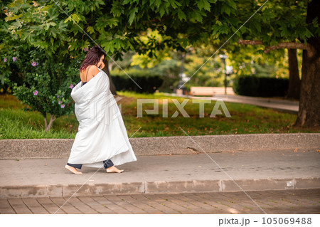 Woman city blanket. Morning in the big city. A blonde woman in a white blanket is enjoying in the city center. Photographed for social media Woman city blanket. Morning in the big city. A blonde woman in a white blanket is enjoying in the city center. Photographed for social media 105069488