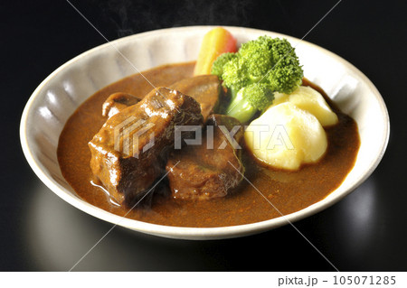 ブロッコリー、人参、ジャガイモが付け合わせてある厚切り牛タンの熱々ビーフシチューを黒背景で撮影 105071285