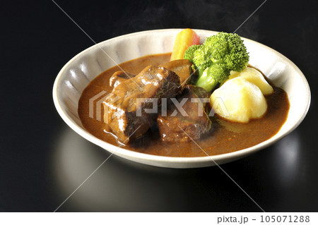 ブロッコリー、人参、ジャガイモが付け合わせてある厚切り牛タンの熱々ビーフシチューを黒背景で撮影 105071288