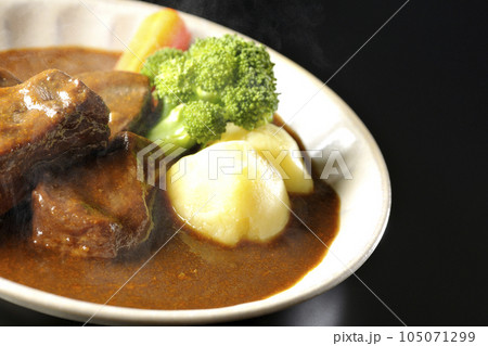 ブロッコリー、人参、ジャガイモが付け合わせてある厚切り牛タンの熱々ビーフシチューを黒背景で撮影 105071299