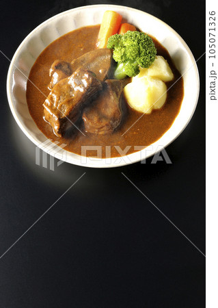 ブロッコリー、人参、ジャガイモが付け合わせてある厚切り牛タンの熱々ビーフシチューを黒背景で俯瞰撮影 105071326