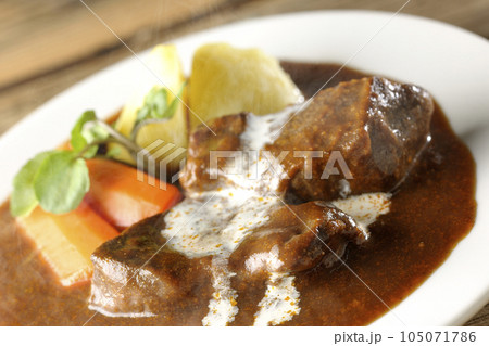クレソン、人参、ジャガイモの付け合わせとクリームがかかっている厚切り牛タンの熱々ビーフシチュー 105071786