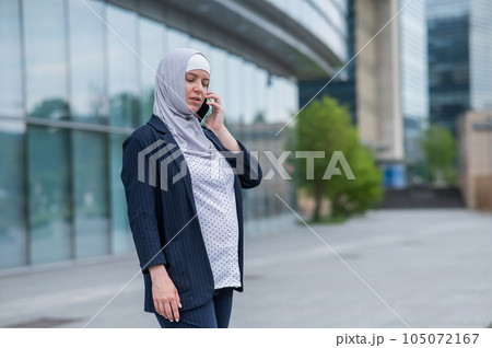 Business woman in hijab and suit talking on smartphone.  105072167