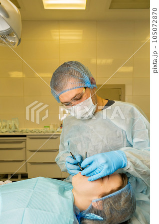 Dental surgeon examines patient's mouth Dental surgeon examines patient's mouth 105072870