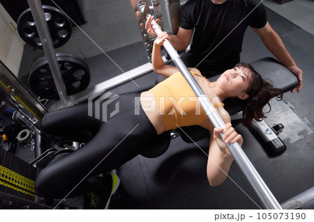 ジムでトレーニングをする女性とサポートするトレーナー ジムでトレーニングをする女性とサポートするトレーナー 105073190