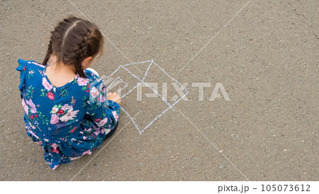 Schoolgirl draws details of house with chalk on asphalt Schoolgirl draws details of house with chalk on asphalt 105073612