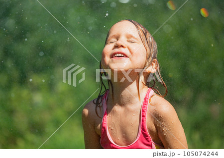 Happy child refreshing with garden sprinkler on a hot summer day Happy child refreshing with garden sprinkler on a hot summer day 105074244