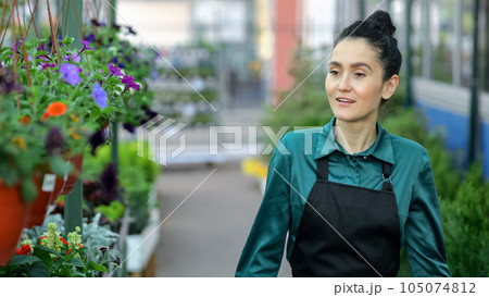 Young woman walks among shelves in flower plants department 105074812