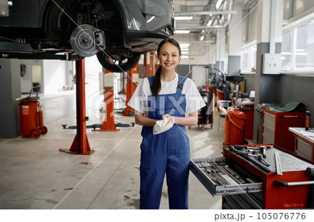 Portrait of beautiful smiling woman mechanic wiping hands with rag 105076776