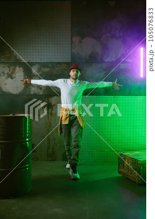 Male break dancer performing on loft stage in green neon light Male break dancer performing on loft stage in green neon light 105076833