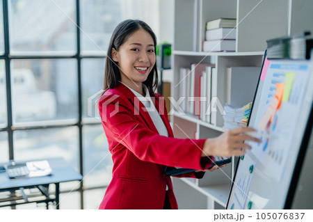 portrait of Beautiful young asian businesswoman presents business profits to colleagues at meeting, explaining business turn over on flipchart to coworkers in office with using tablet. 105076837