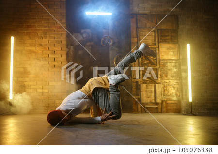 Active stylish guy hip hop dancer training or performing over loft studio 105076838