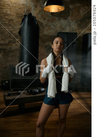 Satisfied woman boxer with towel on shoulders looking at camera 105076924