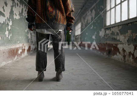 Back view of homeless woman beggar with bottle of alcohol drink in hand 105077041