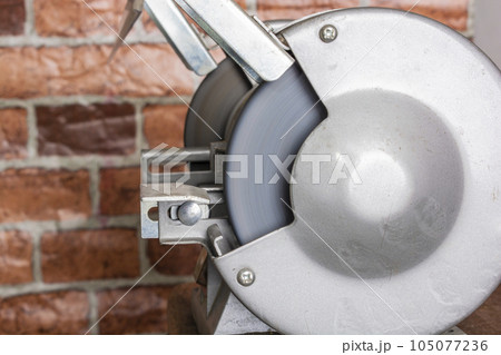 Knife sharpener and hand with blade on wooden table, closeup 105077236