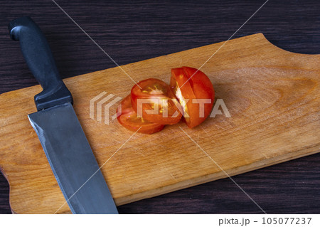 tomato partly sliced with knife and cutting board 105077237
