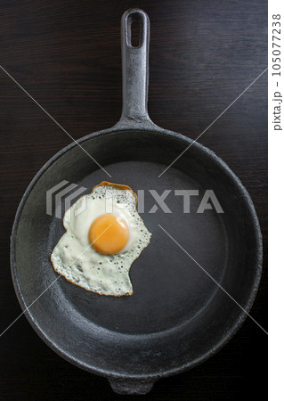 pan with fried eggs on a wooden background pan with fried eggs on a wooden background 105077238
