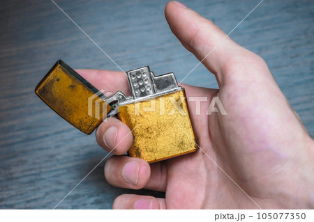 handmade golden lighter on a dark background in yellow and blue tones 105077350