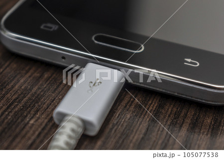 Mobile smart phones charging on wooden desk 105077538