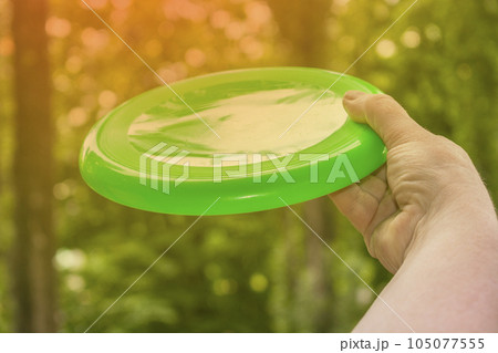 hand throwing a frisbee disc in the park on a summer day hand throwing a frisbee disc in the park on a summer day 105077555
