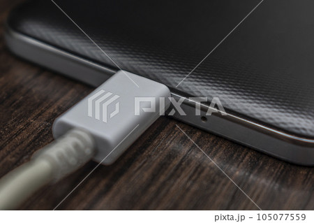 Mobile smart phones charging on wooden desk Mobile smart phones charging on wooden desk 105077559