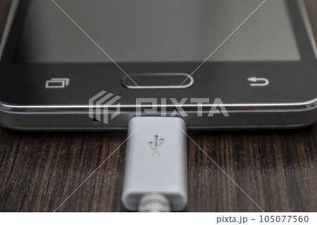 Mobile smart phones charging on wooden desk 105077560