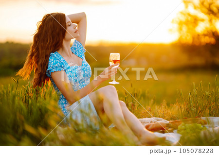 Young woman sits on a plaid with a book. Summer picnic in nature. Healthy food. Young woman sits on a plaid with a book. Summer picnic in nature. Healthy food. 105078228