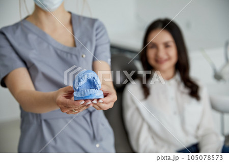 Portrait of young female dentist standing by mid adult woman in clinic. Female dentist repairing patient tooth in dental ambulant 105078573