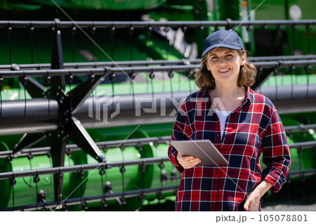 Woman farmer with digital tablet on a background of harvester. Woman farmer with digital tablet on a background of harvester. 105078801