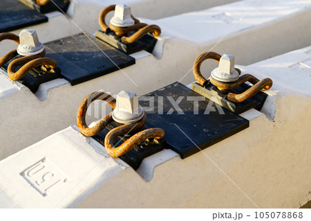 Before track repair stacked new white reinforced concrete railroad track sleepers with rail mounts Before track repair stacked new white reinforced concrete railroad track sleepers with rail mounts 105078868