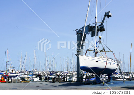 The yacht lifted ashore by a sailboat lift for the maintenance of the underwater part of the hull The yacht lifted ashore by a sailboat lift for the maintenance of the underwater part of the hull 105078881